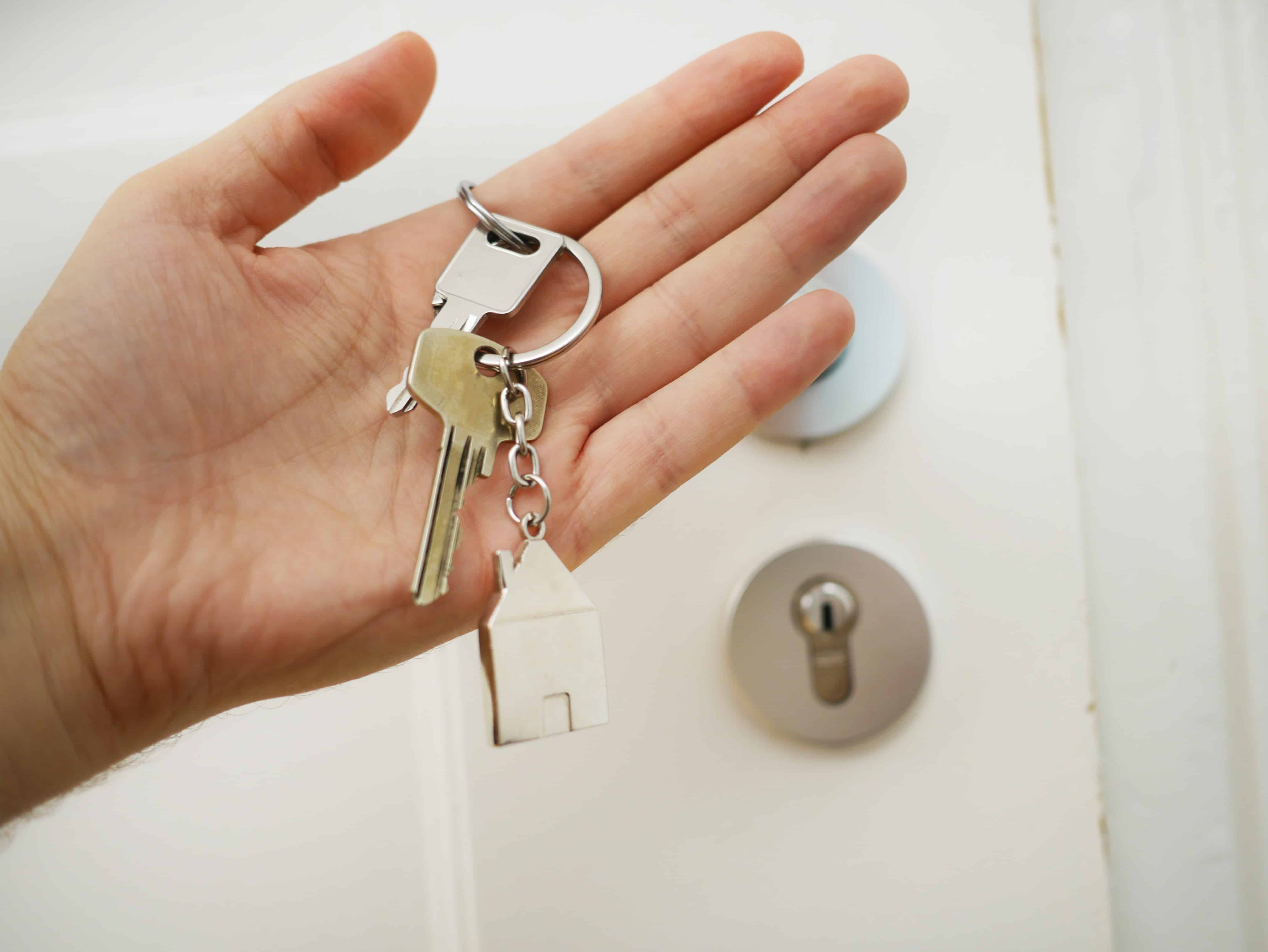 hand holding house keys next to keyhole