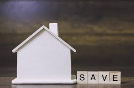 Model white house with Scrabble tiles saying "Save" to the right of the house