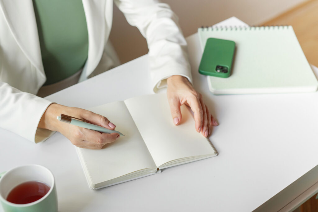 woman working with journal, phone and laptop