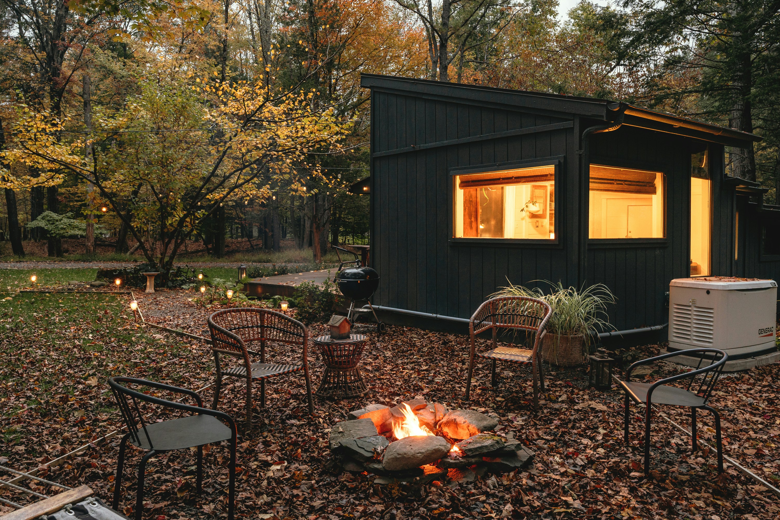 tiny home in the woods with lights on at dusk