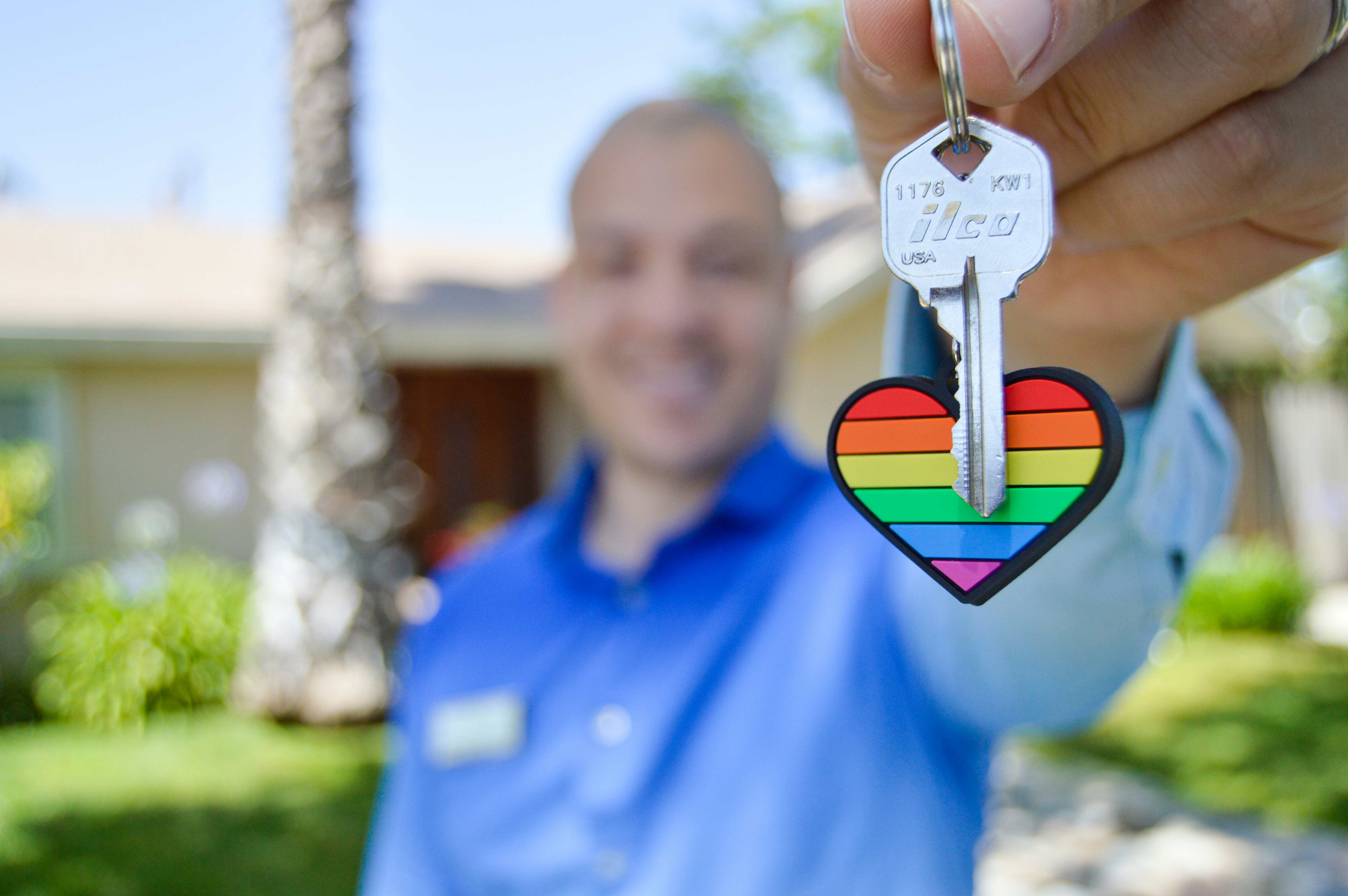 house key on heart key chain held by man in background